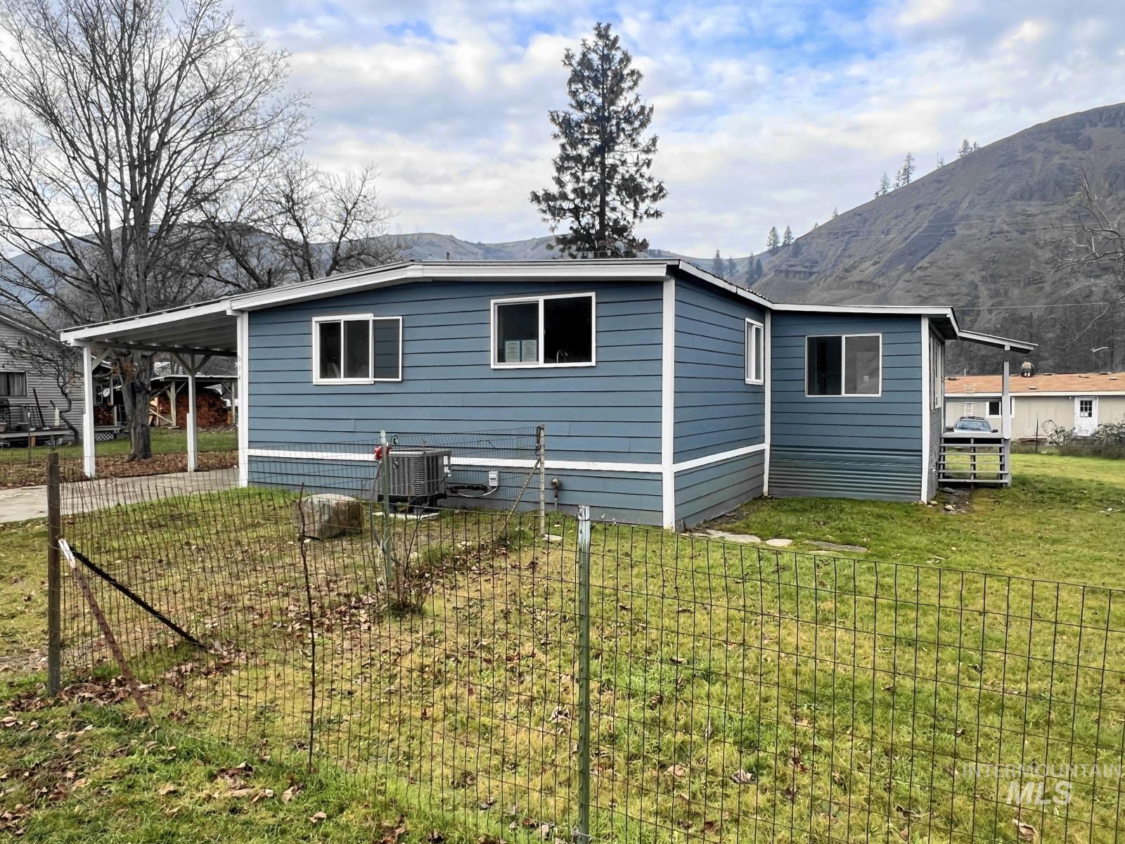 614 Pine Avenue Kooskia, ID 83539 - Photo 21 of 27 View of side of property featuring a lawn, a carport, and a mountain view