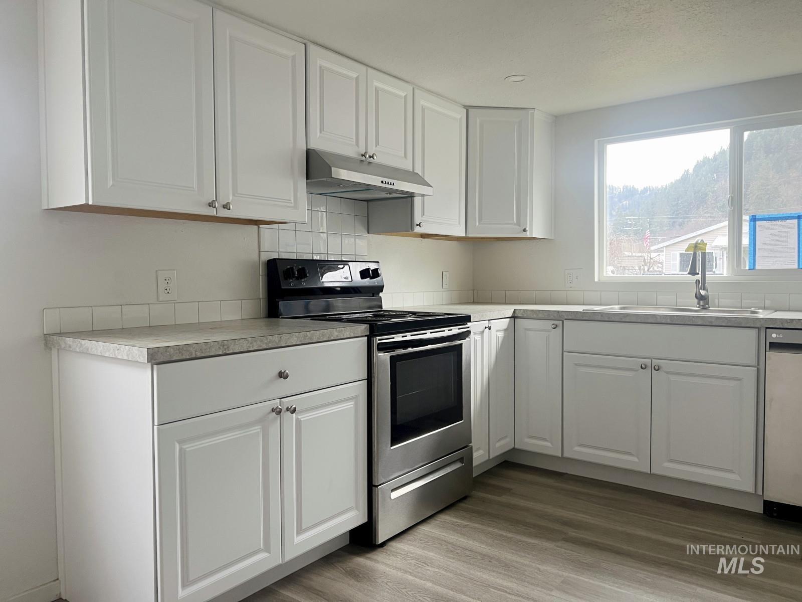 614 Pine Avenue Kooskia, ID 83539 - Photo 9 of 27 Kitchen with white cabinetry, appliances with stainless steel finishes, light countertops, and under cabinet range hood