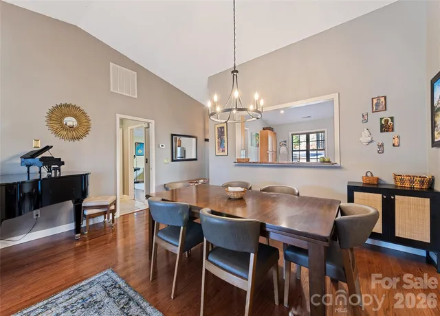 a dining room with wooden floor a chandelier a wooden table and chairs
