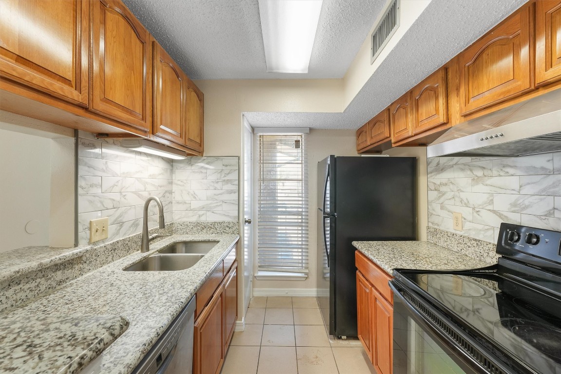 9221 Imogene Street, Unit 9221 Houston, TX 77036 - Photo 2 of 19 a kitchen with granite countertop a sink and a refrigerator