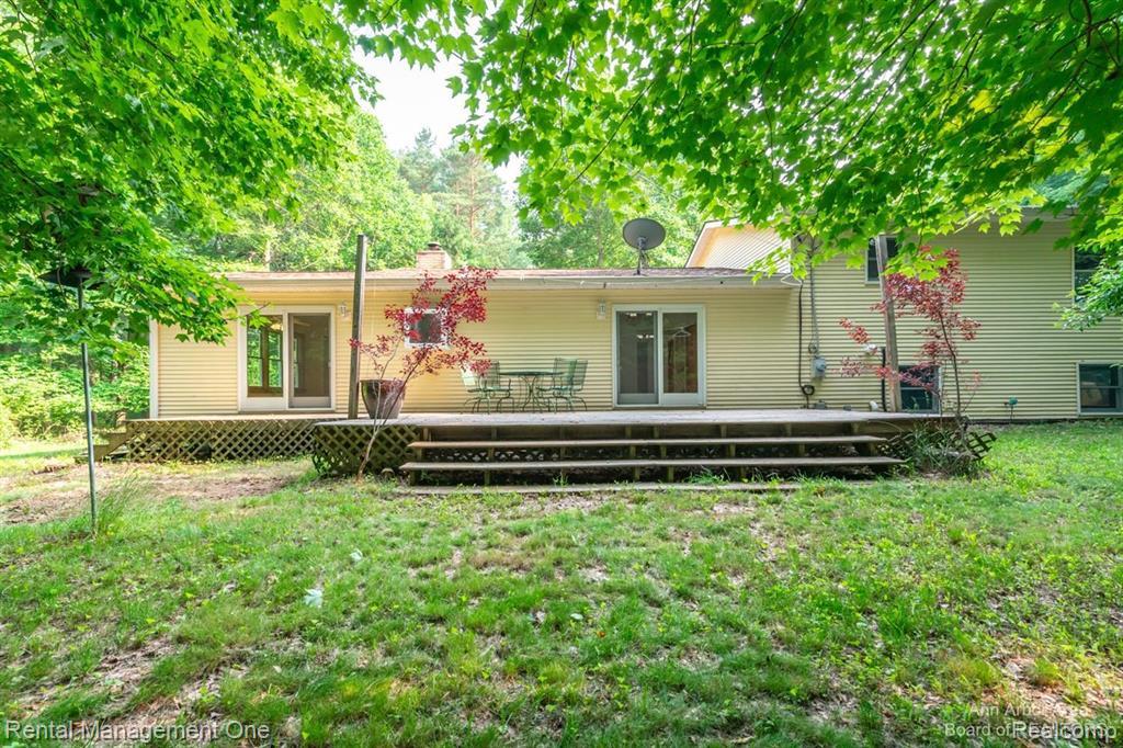 7870 Chamberlin Road Dexter, MI 48130 - Photo 47 of 52 Expansive rear deck with multiple access points, surrounded by mature foliage