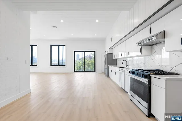 a large kitchen with stainless steel appliances granite countertop a lot of counter space and wooden floor