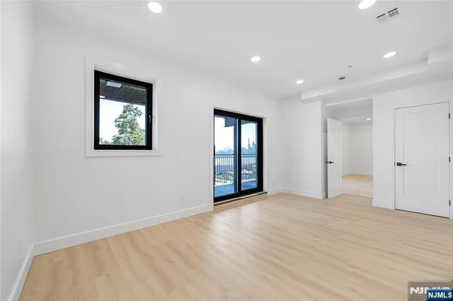 a view of an empty room with window and wooden floor