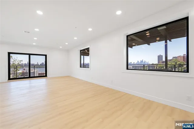 a view of an empty room with a window and a kitchen