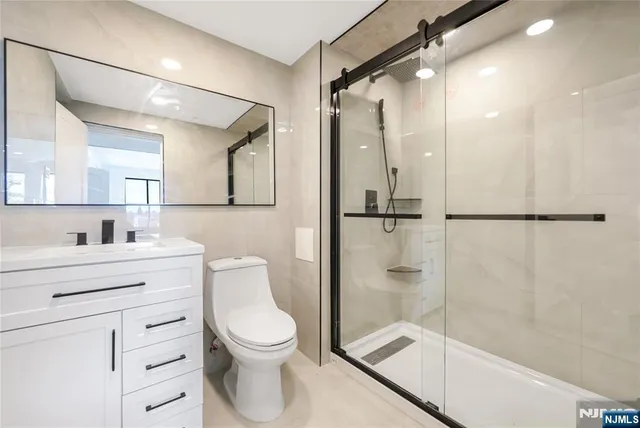 a bathroom with a shower a mirror a toilet and a sink