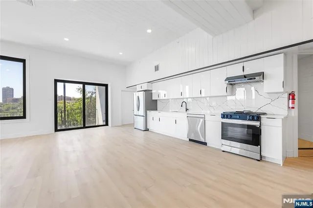 a view of a kitchen with white cabinets and wooden floor