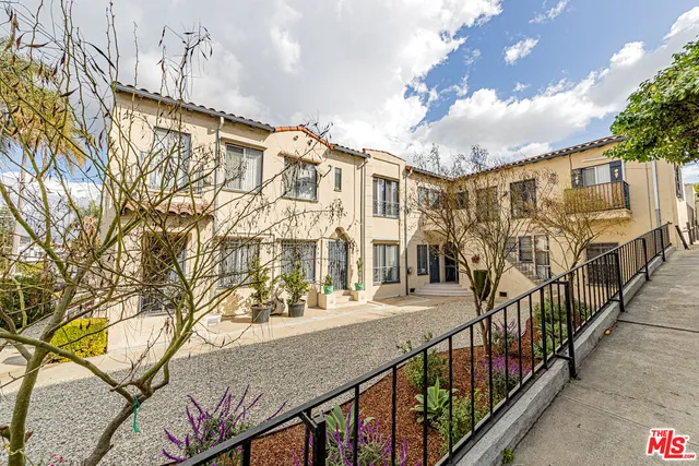 a view of a brick house with large trees and a wooden fence