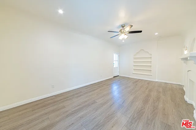 an empty room with wooden floor ceiling fan and window