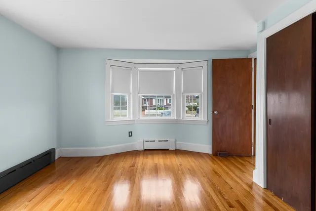 a view of an empty room with window and wooden floor