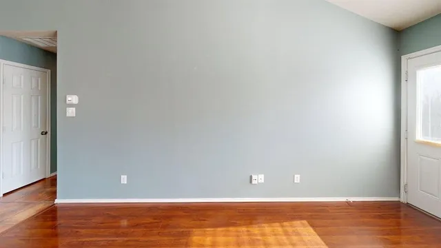 a view of an empty room with wooden floor and a window