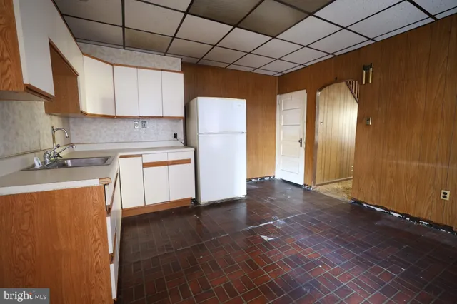 a kitchen with stainless steel appliances granite countertop a refrigerator a sink dishwasher and white cabinets with wooden floor