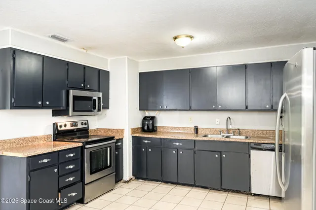 a kitchen with stainless steel appliances granite countertop a stove a sink dishwasher and a refrigerator with wooden cabinets