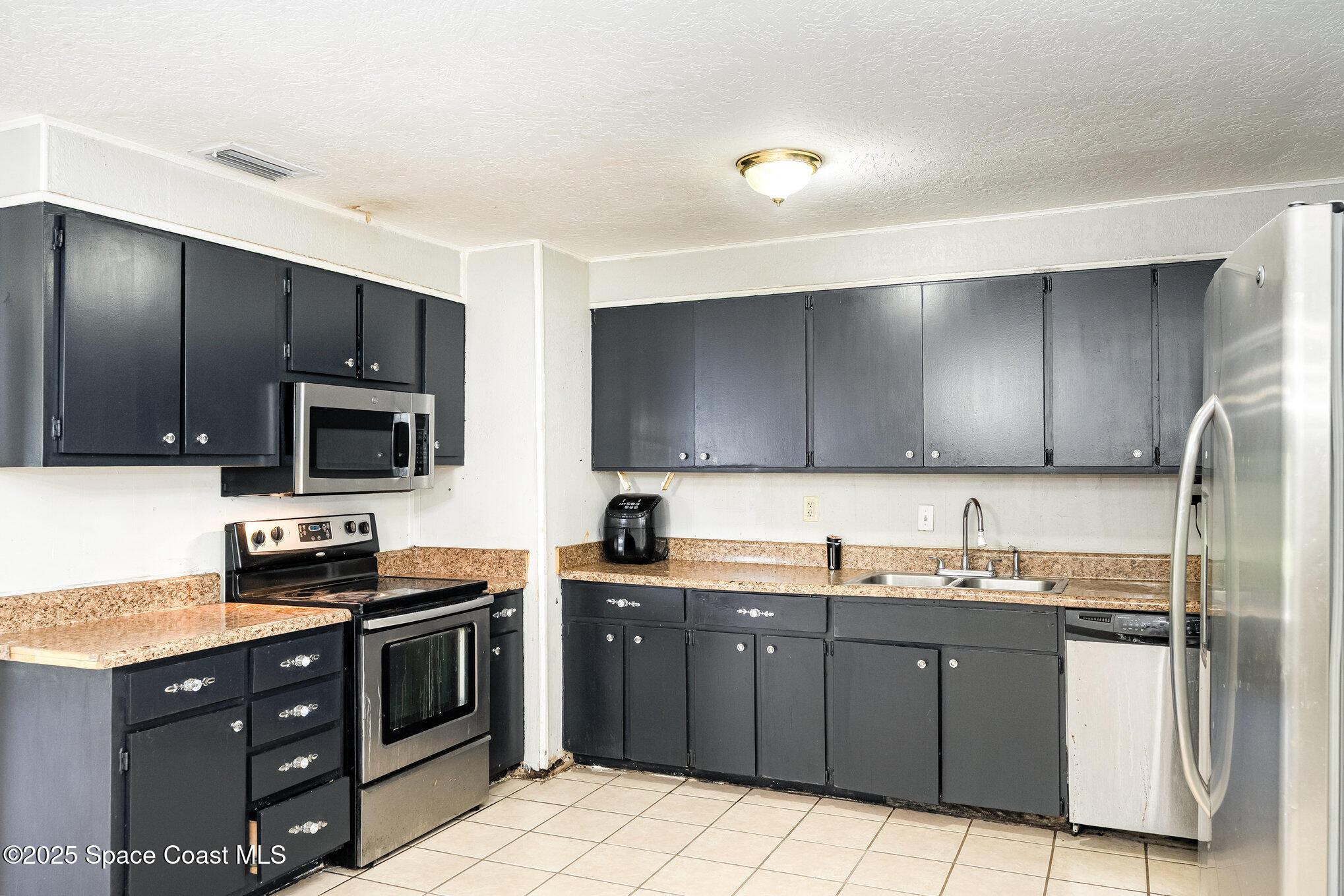 935 South Varr Avenue Rockledge, FL 32955 - Photo 11 of 29 a kitchen with stainless steel appliances granite countertop a stove a sink dishwasher and a refrigerator with wooden cabinets