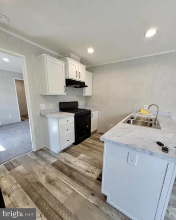 a kitchen with stainless steel appliances granite countertop a sink a stove a refrigerator and white cabinets