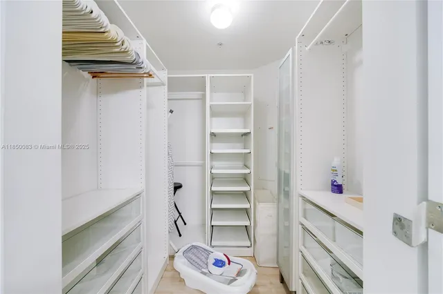 a walk in closet with wooden floor
