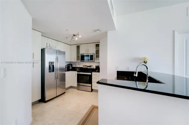 a kitchen with kitchen island granite countertop appliances cabinets and a sink