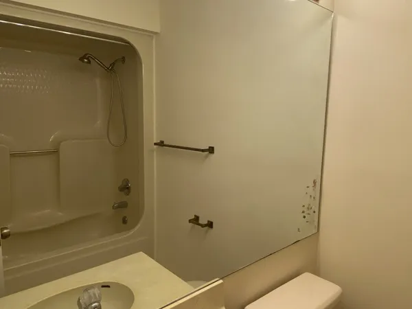 a bathroom with a granite countertop toilet a sink and shower