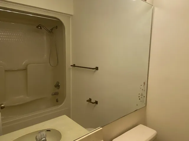a bathroom with a granite countertop toilet a sink and shower