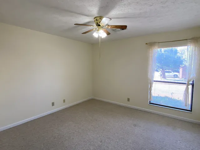 an empty room with windows and chandelier fan