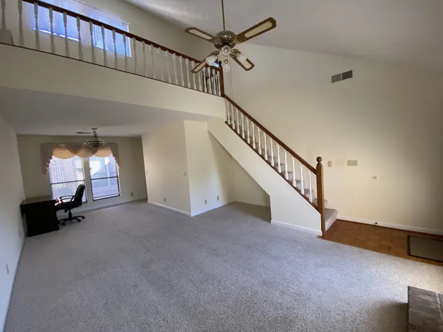 a view of empty room with stairs and a chandelier