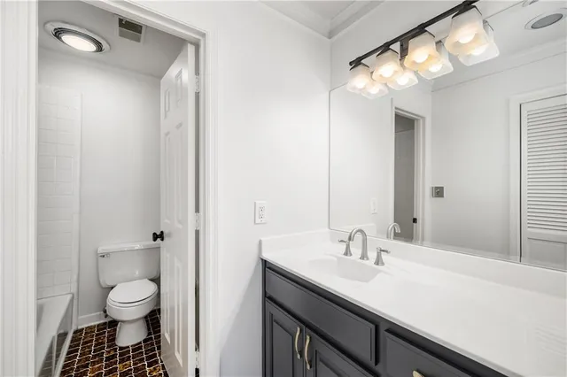 a bathroom with a granite countertop sink a toilet and a mirror