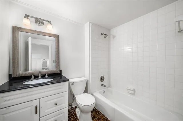 a bathroom with a granite countertop sink a toilet a mirror and bathtub