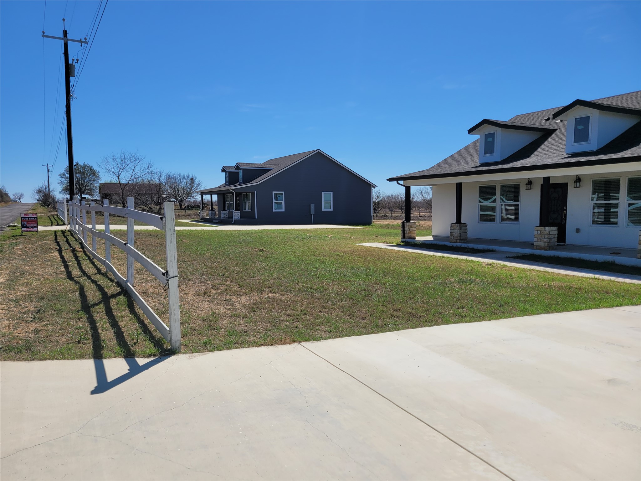 422 County Road 422 Road Stockdale, TX 78160 - Photo 5 of 37 Concrete driveway and a classic white fence lead to two charming, new-build residences with inviting front porches.
