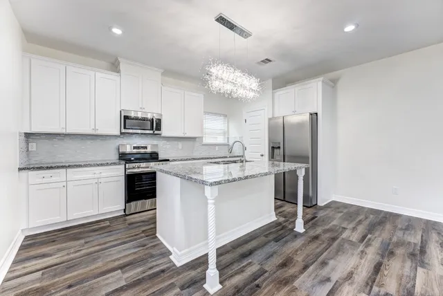 a kitchen with kitchen island granite countertop a stove a sink and a refrigerator
