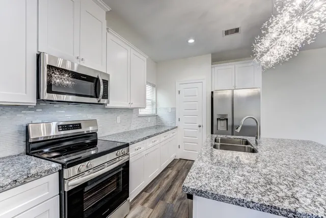 a kitchen with stainless steel appliances granite countertop a stove microwave and sink