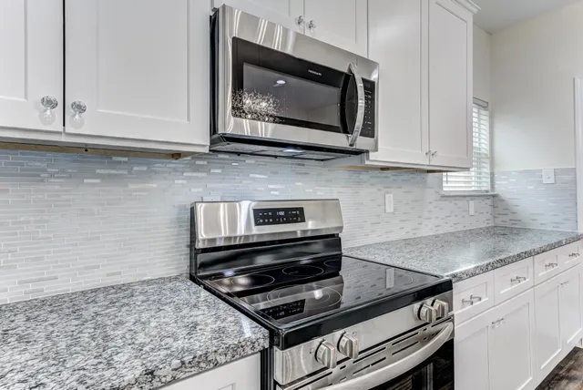 a kitchen with granite countertop a stove microwave and sink