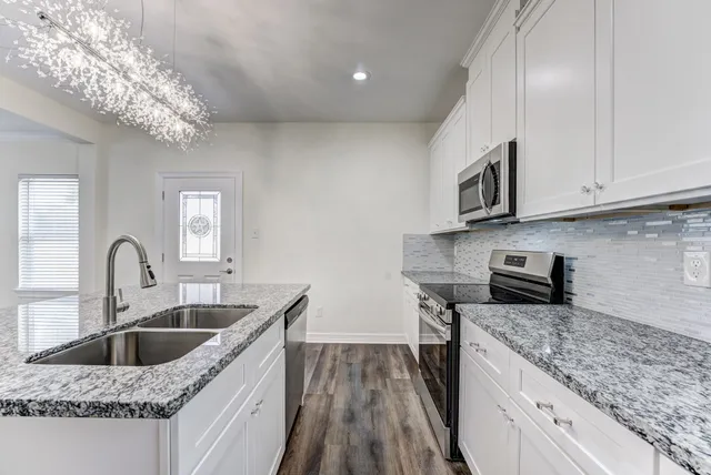 a kitchen with stainless steel appliances granite countertop a sink a stove top oven a counter space and cabinets