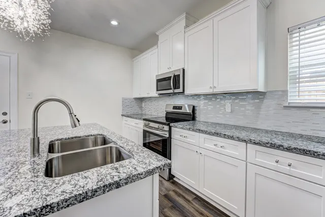 a kitchen with granite countertop white cabinets and stainless steel appliances