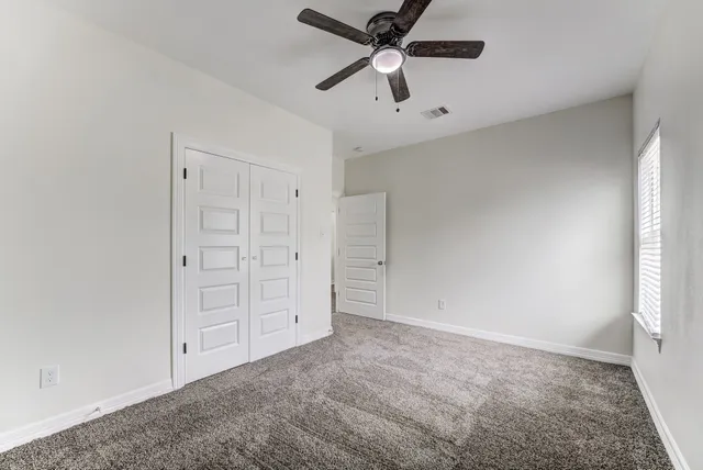 an empty room with closet and fan