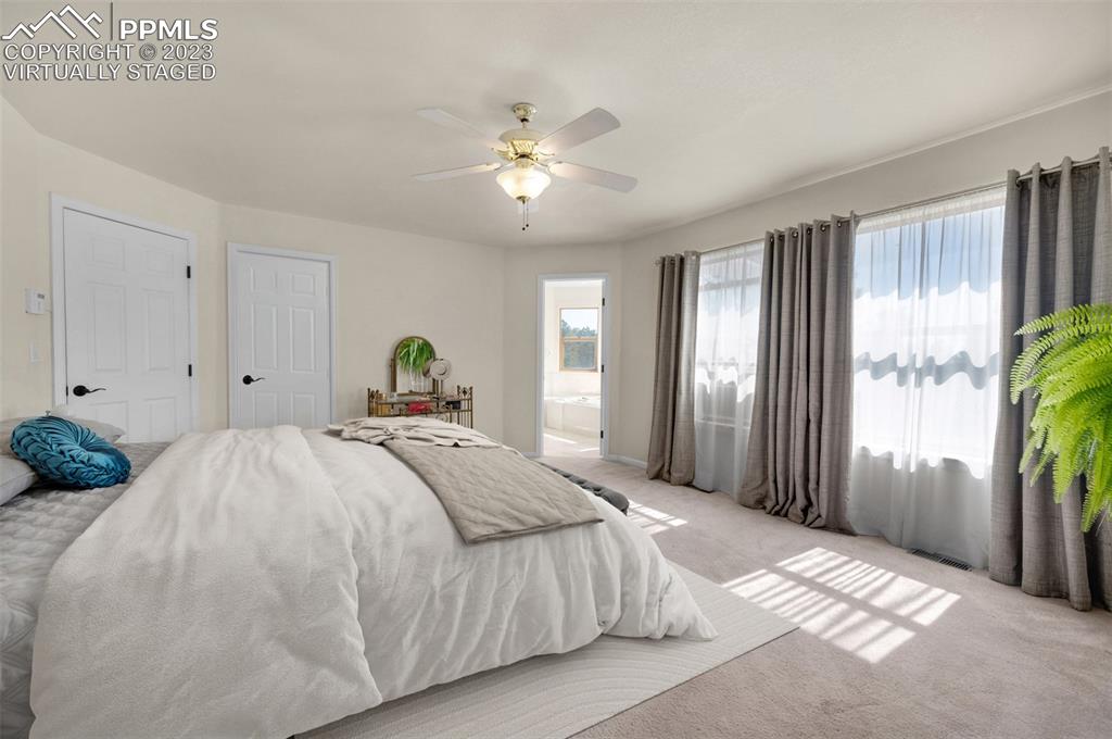 7425 Tobin Road Colorado Springs, CO 80908 - Photo 27 of 49 a spacious bedroom with a bed and a chandelier