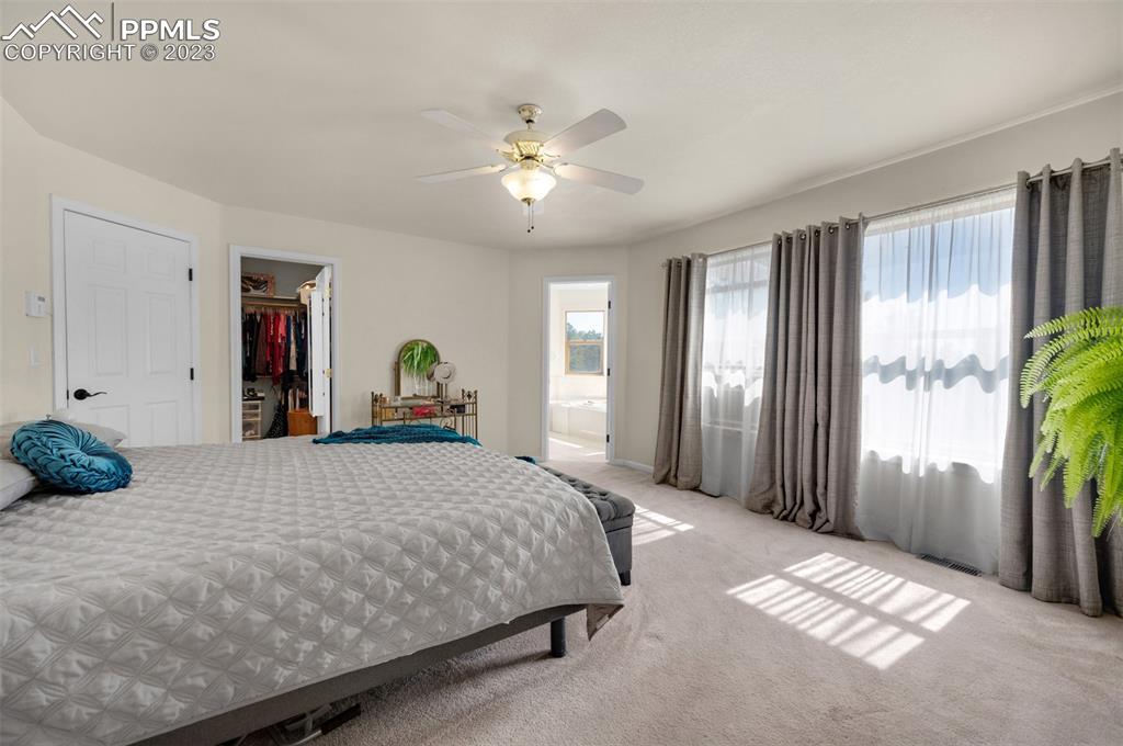 7425 Tobin Road Colorado Springs, CO 80908 - Photo 28 of 49 a bedroom with a large bed and a chandelier