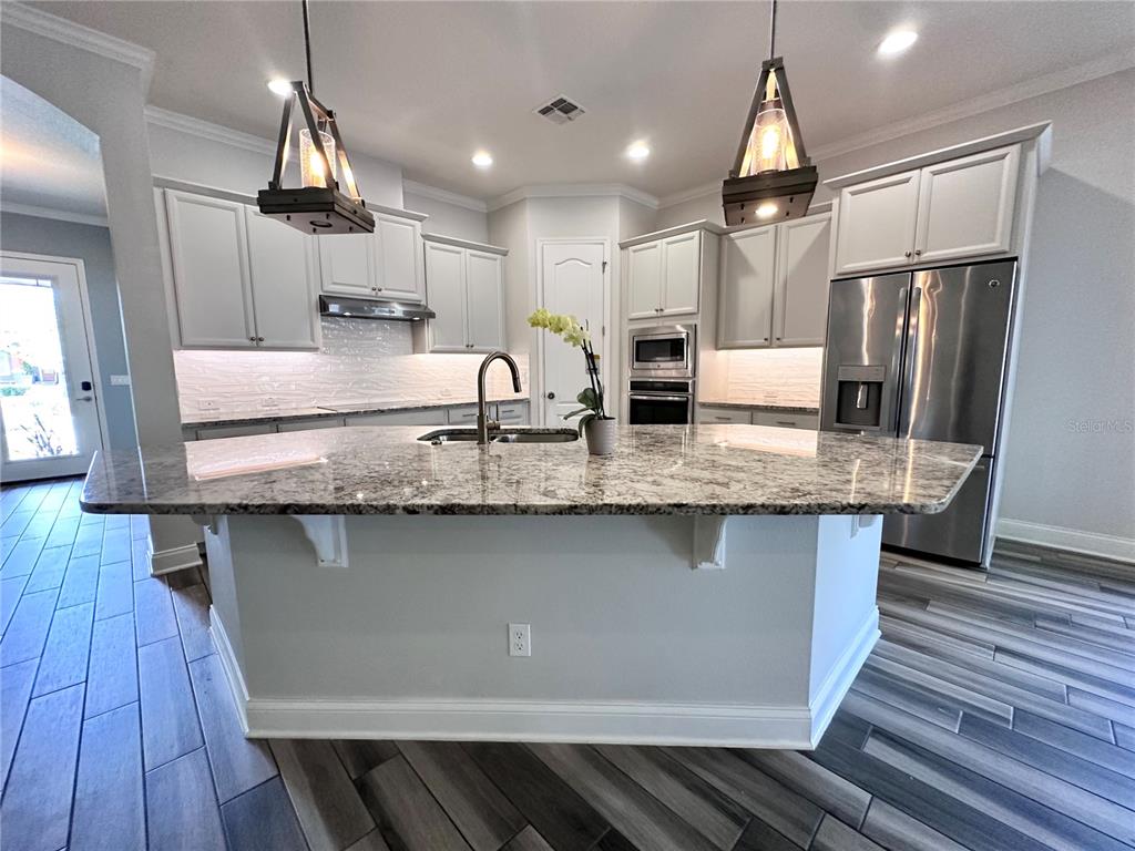 9319 Richet Place Orlando, FL 32827 - Photo 2 of 50 a kitchen with granite countertop a sink a center island stainless steel appliances and cabinets