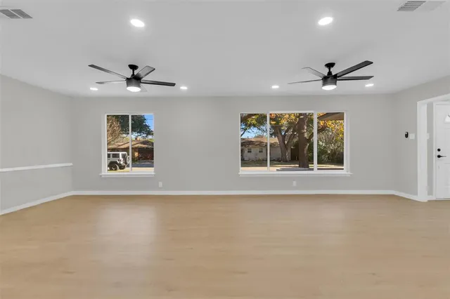 an empty room with windows and ceiling fan