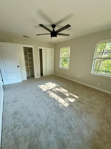 an empty room with windows and ceiling fan