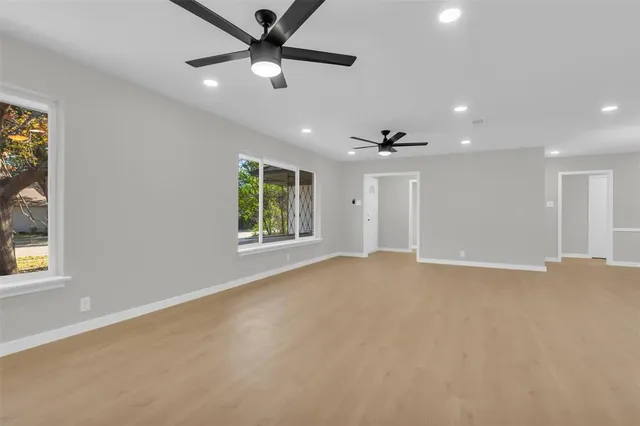 an empty room with windows and ceiling fan
