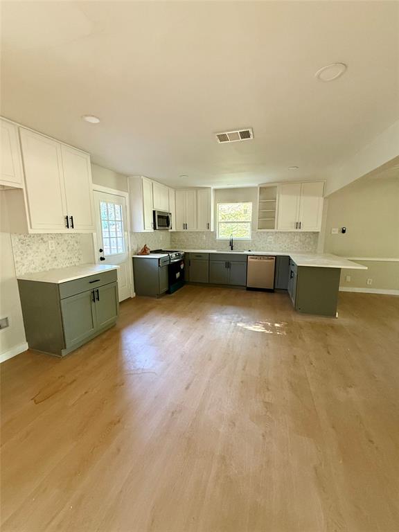 4815 Kelman Street Dallas, TX 75214 - Photo 2 of 16 Kitchen with white cabinets, gray cabinetry, green cabinets, backsplash, and light wood-style floors