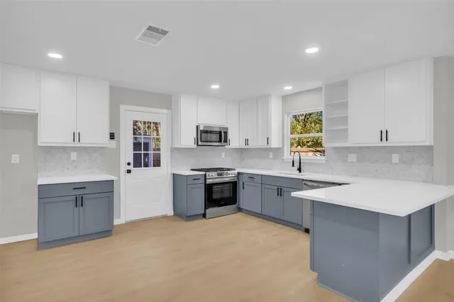 a large kitchen with stainless steel appliances granite countertop a stove sink and cabinets