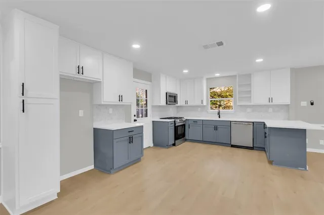 a large kitchen with a lot of white cabinets and stainless steel appliances