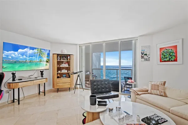 a living room with furniture a flat screen tv and a floor to ceiling window