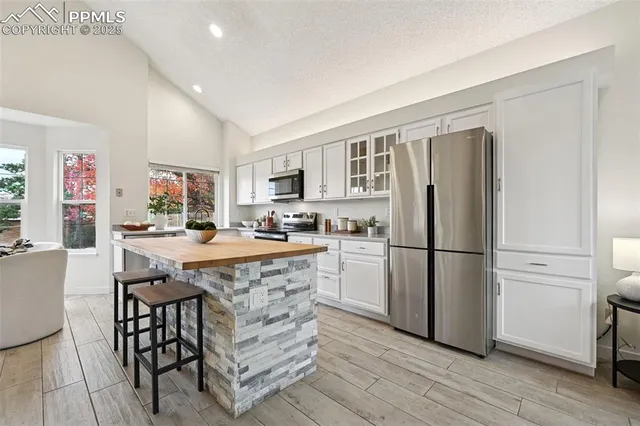 a kitchen with stainless steel appliances granite countertop a refrigerator a stove a sink a dining table and chairs with wooden floor