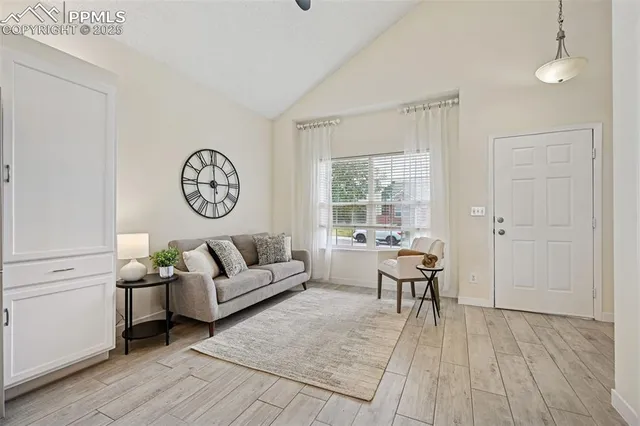 a living room with furniture a clock on wall and a window