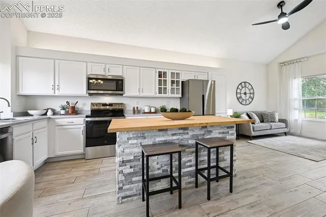 a kitchen with kitchen island granite countertop a stove a sink a dining table and chairs