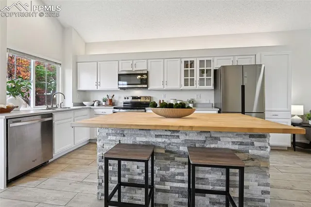a large kitchen with kitchen island a stove a sink a refrigerator dining table and chairs