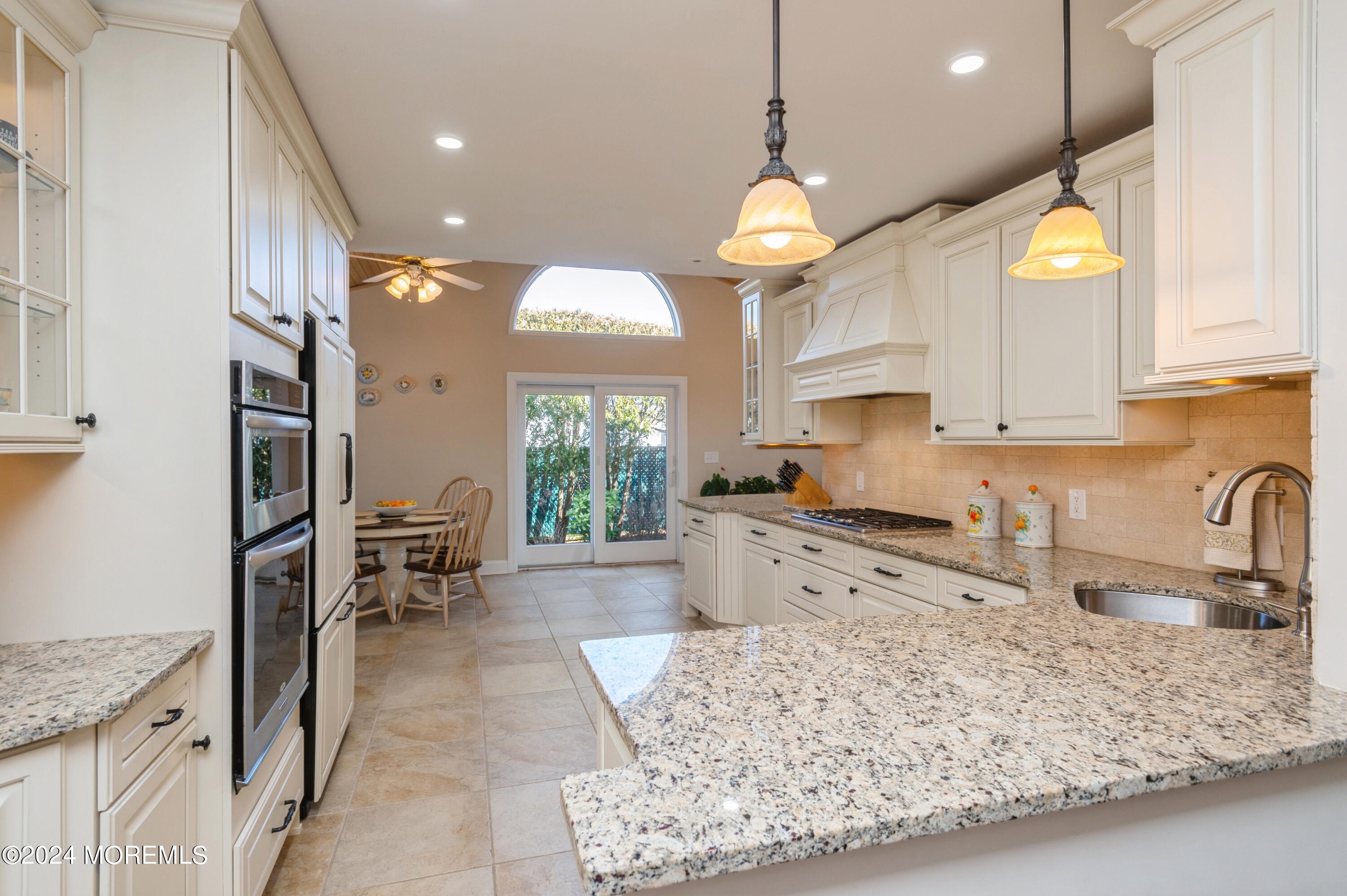 a kitchen with stainless steel appliances granite countertop sink stove and white cabinets with wooden floor