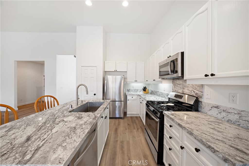 40889 Robards Way Murrieta, CA 92562 - Photo 8 of 36 a kitchen with stainless steel appliances granite countertop a stove top oven a sink a refrigerator with white cabinets and granite countertops