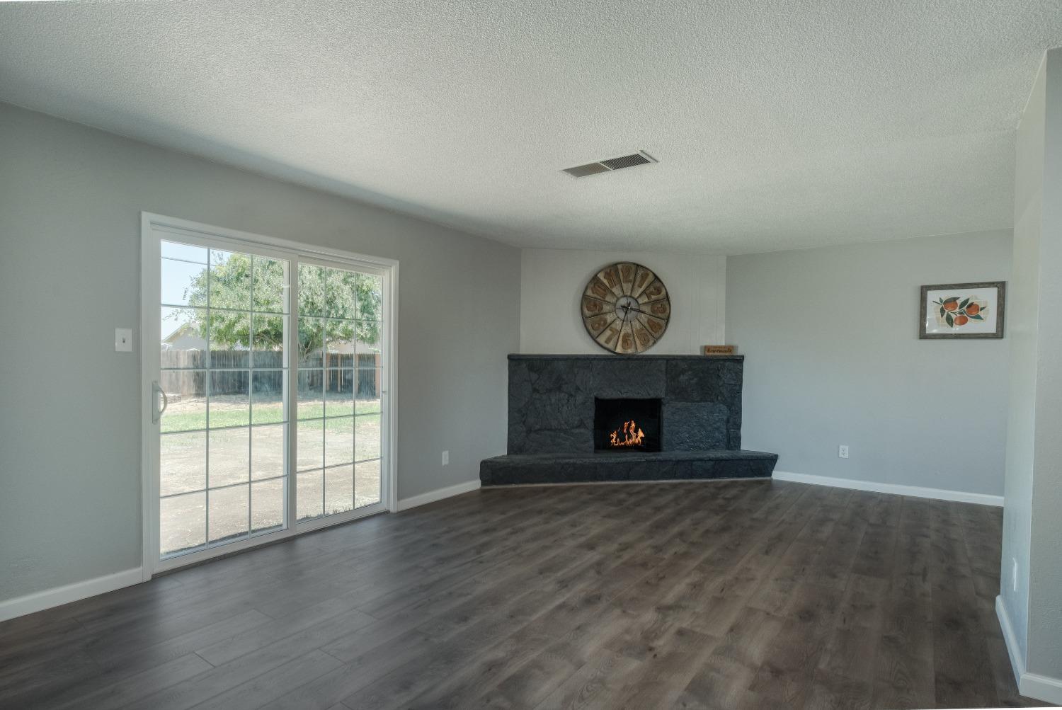 194 West Spring Lane Lemoore, CA 93245 - Photo 6 of 15 a view of an empty room with wooden floor a fireplace and a window